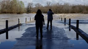 Deux personnes observent les crues au niveau d'un pont submergé à Dions, dans le Gard, le 10 mars 2024