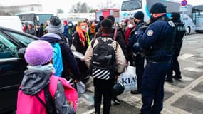 Des personnes sont escortées par la police dans des bus lors de l'évacuation de quelque 300 squatteurs, dont au moins 100 enfants, le 11 février 2021 dans la banlieue bordelaise de Cenon.