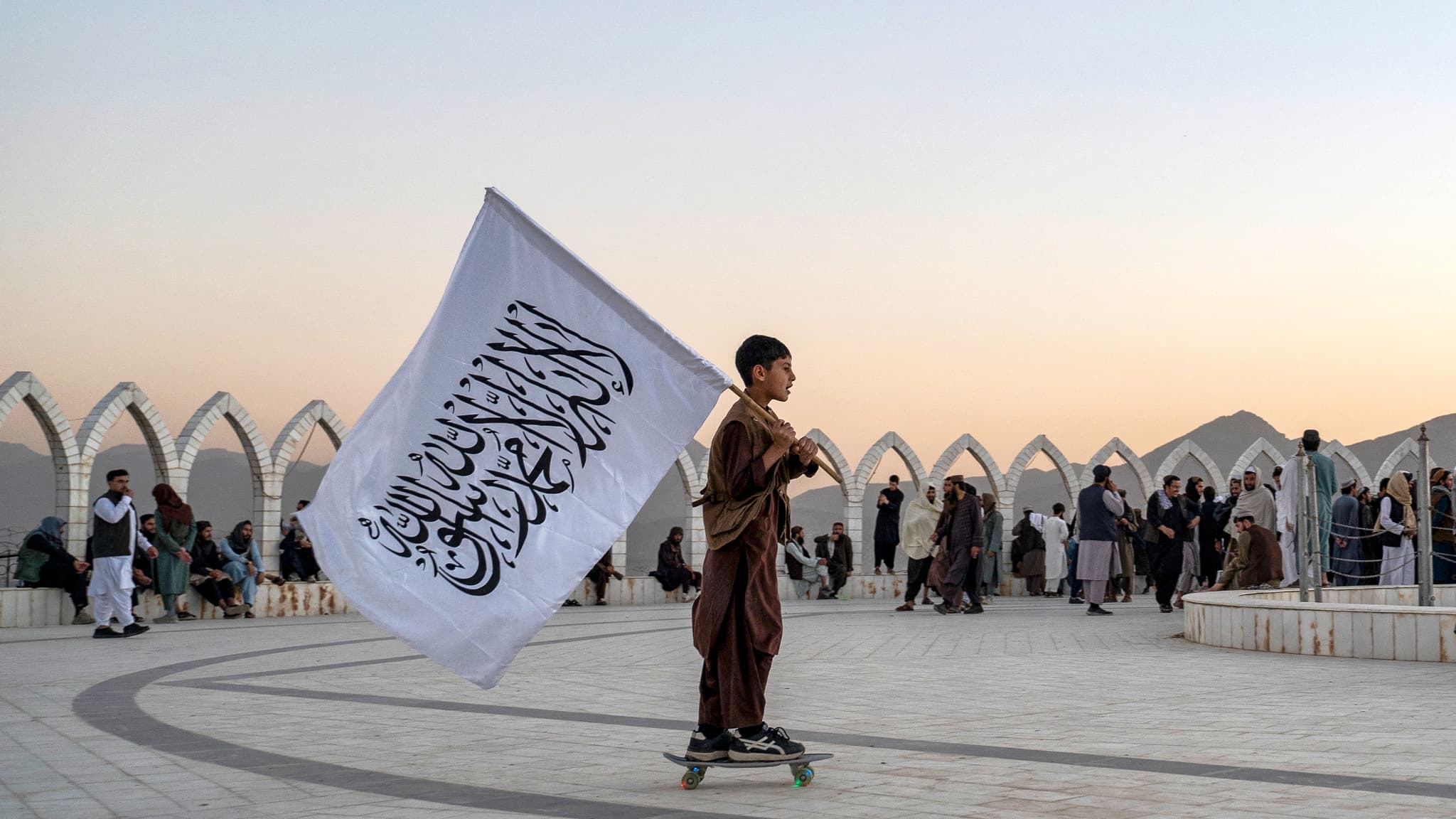 Un jeune garçon se promène en skate avec le drapeau afghan. Un jeune garçon se promène en skate avec le drapeau afghan.