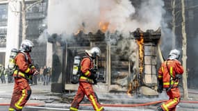 Des pompiers devant l'incendie d'un kiosque sur les Champs-Élysées, le 16 mars 2019.