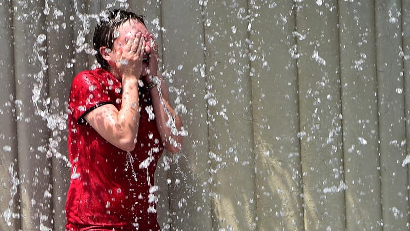 Une jeune fille se rafraîchit dans une fontaine.