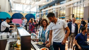 Le président du Comité d'organisation Paris-2024 Tony Estanguet et Nathalie Bellon-Szabo, PDG de Sodexo Live! choisissent leur repas lors d'un test du restaurant du village olympique, à Saint-Denis près de Paris le 25 juin 2024