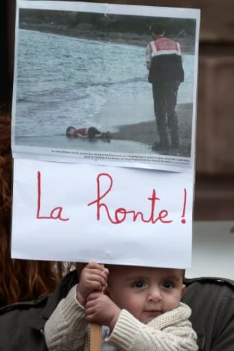 Un enfant tient une pancarte montrant la photo du petit garçon syrien découvert mort sur une plage turque, le 5 septembre 2015 lors d'une manifestation à Strasbourg Un enfant tient une pancarte montrant la photo du petit garçon syrien découvert mort sur une plage turque, le 5 septembre 2015 lors d'une manifestation à Strasbourg