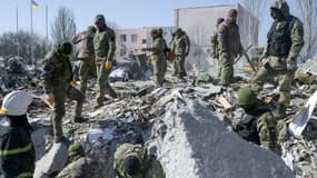 Des soldats ukrainiens cherchent les corps de victimes après une frappe russe sur une caserne à Mykolaiv, dans le sud de l'Ukraine, le 22 mars 2022 