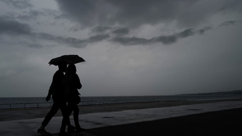 Des personnes s'abritant de la pluie sous un parapluie, le long de la plage sur la "Promenade des Anglais" sur la ville de Nice, le 10 mai 2021 (photo d'illustration)