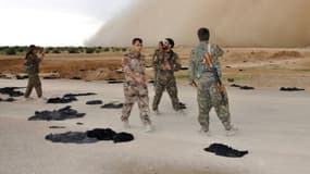 Des membres des Forces démocratiques syriennes (FDS) marchent sur une route jonchée de niqabs abandonnés, près de Raqa, le 2 mai 2017