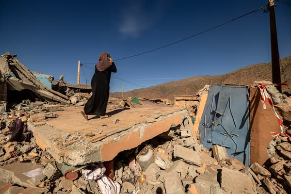 Une femme parle au téléphone sur les décombres d'une maison dans le village de Talat N'Yacoub, dans la province d'al-Haouz, au Maroc, le 11 septembre 2023.