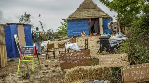 Des pancartes où sont inscrits "Vaccin contre le racisme en vente ici" (G) et "Malgré toutes les difficultés, nous avons toujours le sourire aux lettres" (2ème D), le 1er juin 2015 à Calais Des pancartes où sont inscrits "Vaccin contre le racisme en vente ici" (G) et "Malgré toutes les difficultés, nous avons toujours le sourire aux lettres" (2ème D), le 1er juin 2015 à Calais