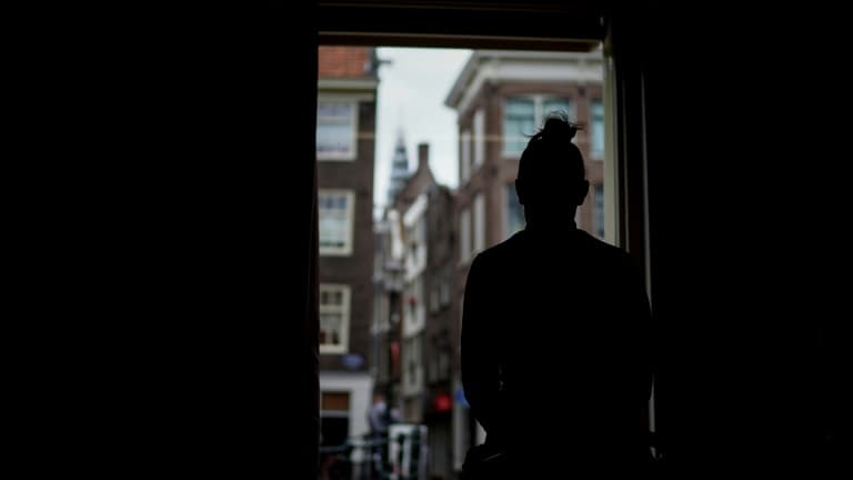 Une femme devant une fenêtre (image d'illustration)