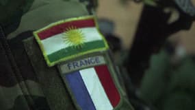 L'uniforme d'un combattant français sur le front syrien, flanqué du drapeau du Kurdistan.
