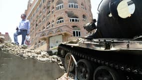 Un homme se tient sur des ruines près d'un tank pendant des échanges de tirs entre les  combattants loyaux au président en fuite Abedrabbo Mansour Hadi et les rebelles chiites Houthis, le 23 août 2015 à Taez, dans le sud-ouest du pays