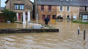 Un homme dans les eaux de crue transporte un parpaing après le débordement de la Vilaine, à Pont-Rean, le 27 janvier 2025.