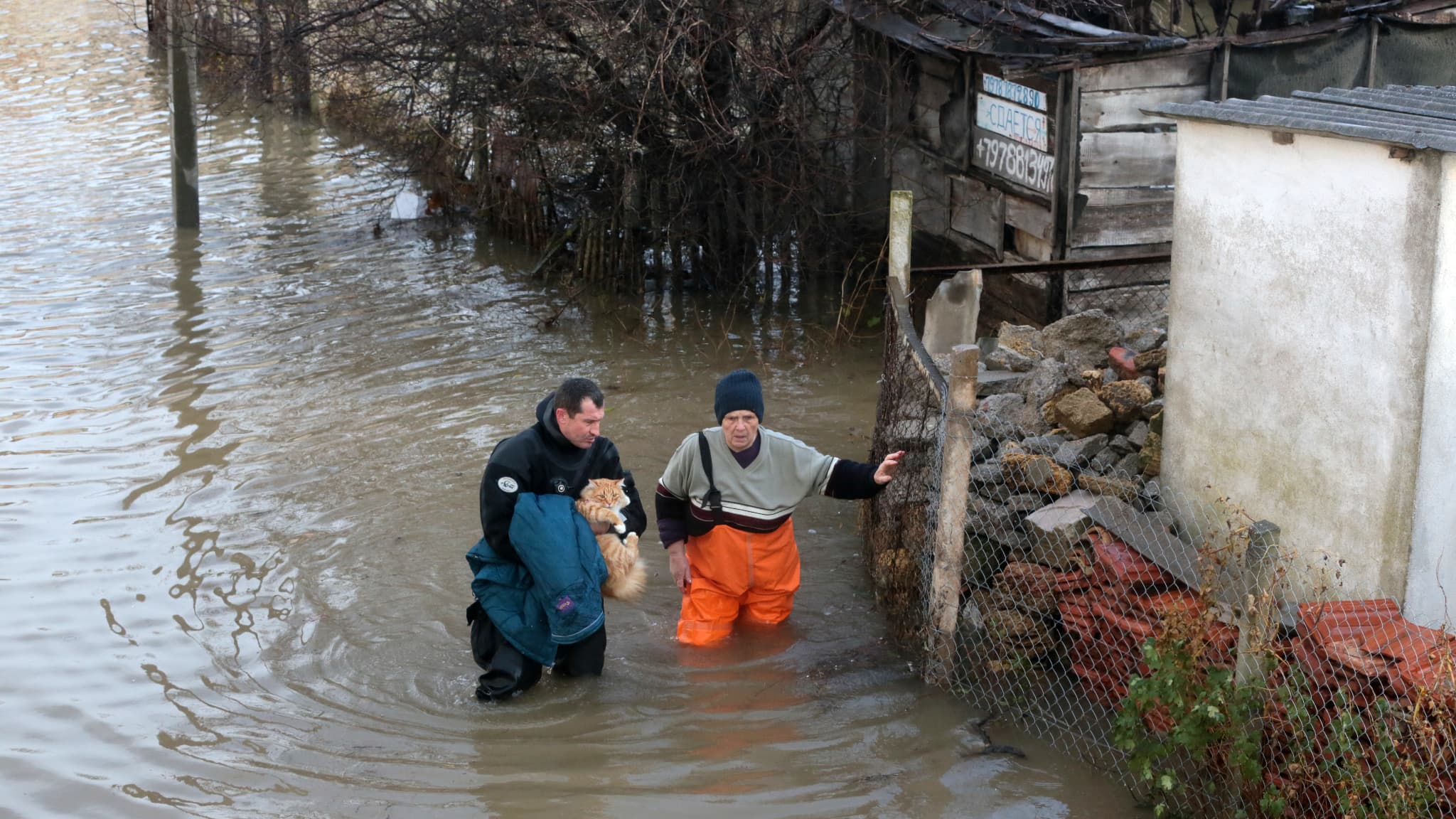 Un sauveteur porte un chat et aide une femme lors de l'évacuation des habitants du village inondé de Pribrezhnoe, en Crimée, le 27 novembre 2023.