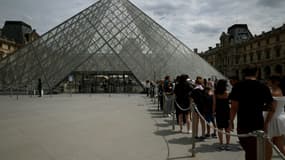 Des visiteurs font la queue devant la pyramide de l'architecteIeoh Ming Pei au musée du Louvre à Paris, le 11 juillet 2024