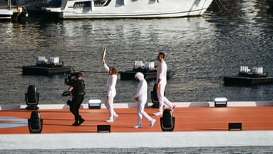 L'athlète Nantenin Keïta porte la flamme devant Jul et Florent Manaudou, sur le Vieux Port de Marseille, le 8 mai 2024