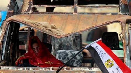 Manifestant endormi dans un minibus incendié place Tahrir au Caire. Le nouveau gouvernement égyptien formé par Hosni Moubarak s'est réuni au complet lundi, au quatorzième jour de la contestation du régime qui se poursuit malgré l'ouverture de négociations