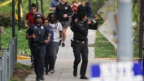 Des policiers escortent des passant dans un quartier du nord de Washington D.C., vendredi 22 avril 2022, après d'un homme a ouvert le feu sur la foule depuis son immeuble