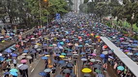 Des dizaines de milliers de manifestants ouvrent leur parapluie en défilant à Hong Kong, le 18 août 2019