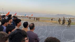 Des soldats américains en position sur le tarmac de l'aéroport de Kaboul alors que des Afghans attendent de pouvoir quitter le pays, le 16 août 2021 