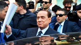L'ancien chef du gouvernement italien Silvio Berlusconi quitte un bureau de justice de Milan, le 23 avril 2014, entouré de ses gardes de sécurité.
