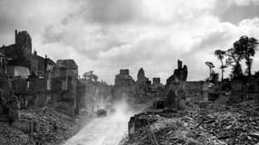 Des véhicules blindés américains sur une route bordée de ruines dans la ville de Saint-Lo, en 1944, pendant la Seconde Guerre mondiale