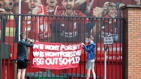 Des supporters accrochent une banderole devant Anfield