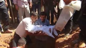 Le père du petit Aylan Kurdi (c) tient entre ses bras la dépouille de son fils avant son enterrement à Kobané en Syrie, le 4 septembre 2015
