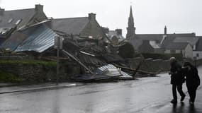 Des piétons passent devant un entrepôt détruit à Porspoder après le passage de la tempête Ciaran, le 2 novembre 2023 dans le Finistère