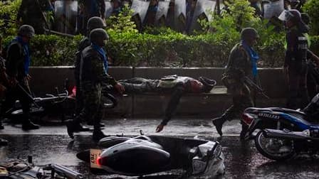 Soldats transportant le corps d'un de leurs camarades tué dans des affrontements dans la banlieue nord de Bangkok. Ces violents affrontements entre l'armée thaïlandaise et les opposants au gouvernement ont par ailleurs fait au moins 18 blessés. /Photo pri