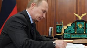 Vladimir Poutine signe des documents au Kremlin, à Moscou, le 20 mars.
