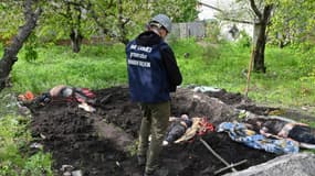 Un homme se tient devant les corps exhumés de civils d'une habitation du village de Stepanky, près de Kharkiv, en Ukraine, le 11 mai 2022