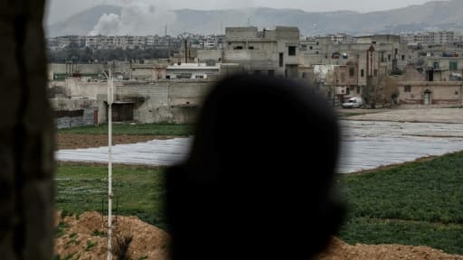 Un Syrien observe un pilier de fumée s'élever au-dessus de la ville de Douma, près de Damas, le 23 mars 2017
