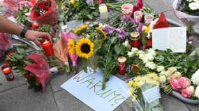 Bougies, fleurs et note où est inscrit "Pourquoi" rendent hommage aux neuf victimes du forcené, à l'entrée du centre commercial de Munich le 23 juillet 2016