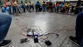 Des personnes chargent leur téléphone avec une batterie externe lors d'une coupure de courant au Venezuela ce vendredi 30 août 2024