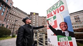 Un homme installe une banderole "Allez Silvio !" devant l'hôpital San Raffaele où l'ancien Premier ministre italien, Silvio Berlusconi, est hospitalisé à Milan, le 7 avril 2023