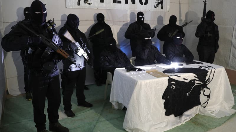 Des membres du Front de Libération Nationale Corse (FLNC), cagoulés, vêtus de treillis militaires et armés de fusils, tiennent une conférence de presse dans un lieu tenu secret sur l'île méditerranéenne française de Corse en janvier 2024.