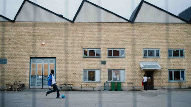 Un enfant joue au ballon devant un centre de réfugiés dans la banlieue de Stockholm.