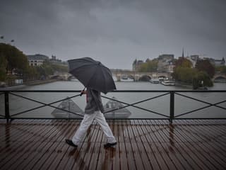 Une personne s'abrite sous un parapluie en traversant le pont des Arts durant la dépression Kirk qui provoque de fortes pluies sur le centre de Paris, le 9 octobre 2024. 