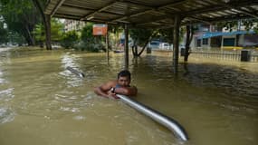 Un homme s'accroche à une barrière en attendant d'être évacué par les secouristes à Shah Alam en Malaisie, touchée par des inondations, le 20 décembre 2021.