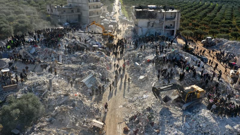 Une photo aérienne montre des sauveteurs fouillant les décombres des bâtiments à la recherche de victimes et de survivants dans le village de Besnaya, dans la province d'Idleb, au nord-ouest de la Syrie, tenue par les rebelles, à la frontière avec la Turquie, suite à un tremblement de terre, le 7 février 2023.