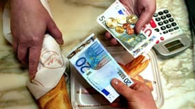 Une personne achète sa baguette de pain, le 2 janvier 2002, dans une boulangerie de Lille, avec un billet de 20 euros