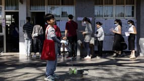 Un enfant joue alors que les gens font la queue pour voter lors de l'élection présidentielle dans un bureau de vote d'une école primaire de la ville de New Taipei, le 13 janvier 2024.