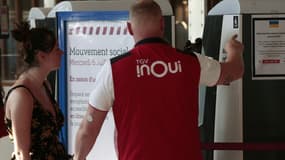 Un employé de la SNCF donne des informations à une passagère Gare de Lyon à Paris, le 6 juillet 2022, alors qu'une grève affecte la circulation des trains