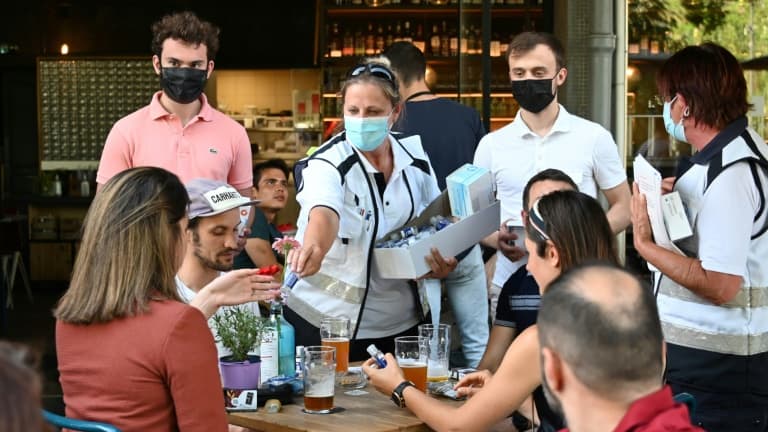 Des médiateurs délivrent du gel hydroalcoolique à des consommateurs le 12 juin 202 à la terrasse d'un bar de Strasbourg après la découverte d'un cluster du variant delta du covid dans une école d'arts de la ville.