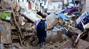 Une personne dans une rue bloquée par des débris et des voitures empilées à Paiporta, dans la région de Valence, dans l'est de l'Espagne, le 4 novembre 2024, à la suite d'inondations dévastatrices.