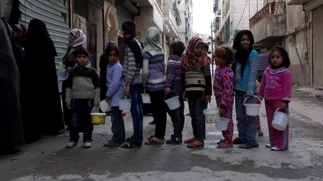 Des enfants attendent de recevoir des rations de nourriture, dans la banlieue d'Alep, en Syrie, en novembre 2014. 