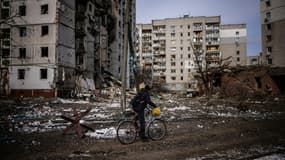 Un homme passe en bicyclette devant des immeubles d'habitation endommagés par des bombardements, à Tcherniguiv (Ukraine), le 4 mars 2022