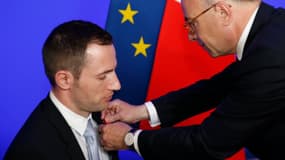 Un commissaire de police, paraplégique après avoir été blessé au Bataclan lors des attentats du 13 novembre, a reçu les insignes de chevalier de la Légion d'honneur des mains du ministre de l'Intérieur, Bernard Cazeneuve, le 22 juin 2016.