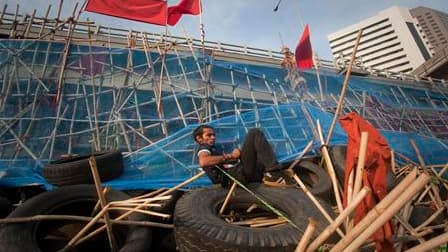 Une "chemise rouge" sur une barricade de bambous et de pneus érigée dans le quartier de Silom à Bangkok. La crainte d'un violent affrontement devient plus pressante en Thaïlande, où les manifestants anti-gouvernementaux ont bloqué l'entrée de convois de p