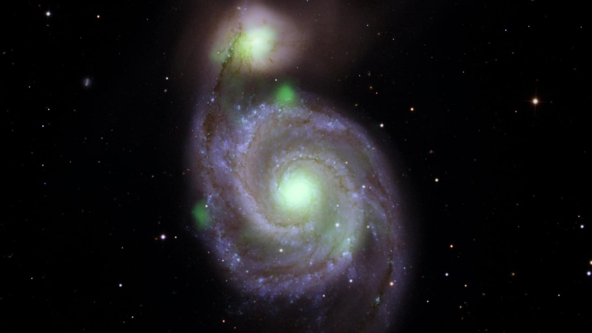 Des sources vertes brillantes de rayons X à haute énergie capturées et superposées sur une image optique de la galaxie Whirlpool (la spirale au centre de l'image) et de sa galaxie compagne, M51b (la brillante au-dessus du Whirlpool). 